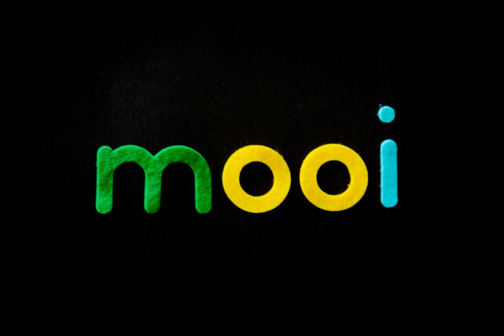 Vibrant and modern typography spells 'mooi' in green, yellow, and blue on black.