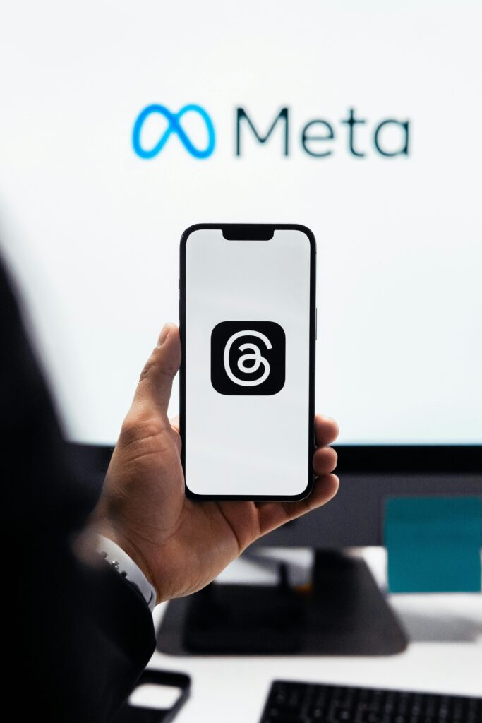 Close-up of a person holding a smartphone displaying Meta's threads logo.