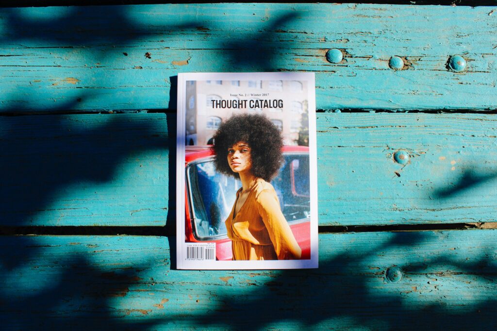 Thought Catalog magazine lies on a textured wooden surface, showcasing a stylish cover with vibrant shadows.